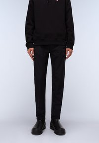 Black sweatshirt with a logo detail, paired with black slim-fit pants and black ankle boots. Smooth texture and minimalistic design elements.