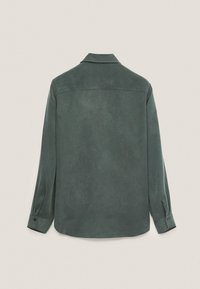 Chemise manches longues vert foncé vue de dos avec un col et des poignets boutonnés sur un fond uni clair.
