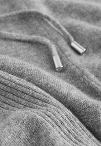 Hallide hall kinnas, millel on sile tekstuur ja peen soonikpattern, varustatud metallist agletidega nööridel.