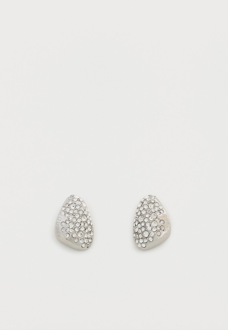 Petites boucles d'oreilles triangulaires en argent ornées de strass clairs regroupés sur un fond blanc.