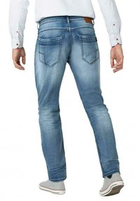 Light blue denim jeans with a slim fit, faded look, and two back pockets, paired with gray sneakers and a white button-up shirt.