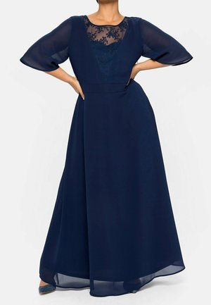 Marineblauwe maxi-jurk met een doorschijnende, met kant verfraaid lijfje, uitlopende mouwen en een vloeiende chiffon rok. Zachte textuur, elegante silhoutte.