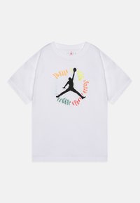 Bílý tričko s krátkým rukávem a černým logem Jumpman ve středu, obklopené barevným kruhovým textem s nápisem "Jordan."