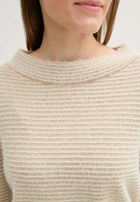 Beige Pullover mit einem strukturierten, gerippten Design und einem breiten, runden Kragen. Weiches, leichtes Material mit einem leicht flauschigen Aussehen.