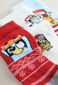 Three pairs of cotton socks: red with white snowflakes, white with cartoon designs, and light blue. Each has distinct patterns and colors.