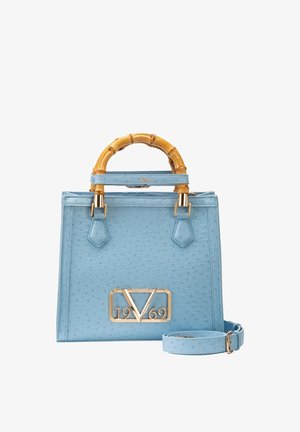 Lichtblauwe handtas met bamboe handvatten, gouden 1969-logo en bijpassende verstelbare schouderriem ernaast.