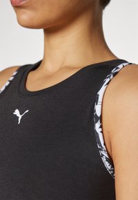 Canottiera sportiva nera senza maniche con logo bianco, dotata di spalline a fantasia in bianco e nero, realizzata in tessuto morbido ed elastico.