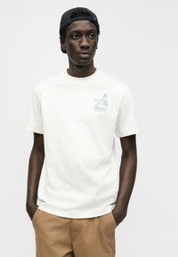 Λευκό βαμβακερό t-shirt με κοντά μανίκια, με μπλε γραφικό ενός βουνού και το κείμενο "The North Face Yosemite, CA" στο στήθος.