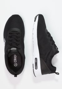 Svarta mesh träningsskor med vita sulor. Har en vadderad krage, snörningsdesign och en synlig luftkuddsenhet i hälen.