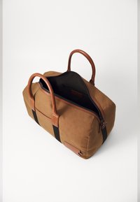 Borsa duffel in tela marrone con manici in pelle e dettagli neri. Presenta una chiusura con zip e una tasca interna per lo stoccaggio.