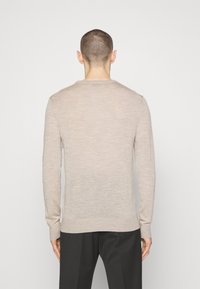 Jasnobeżowy sweter z długim rękawem i okrągłym dekoltem. Wykonany z miękkiego materiału, posiada ribbowany dół i ściągacze. Prosty, niezdobiony design.