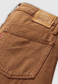 Bruine denim jeanszak met leren merkpatch van Levi Strauss & Co. en een rode Levi's stoffenlabel op de zijnaad.