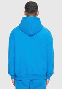 Niebieska bluza z kapturem, miękka tkanina, luźny krój, długie rękawy, duży kaptur, ściągacze przy rękawach i hemie, minimalistyczny design, jednolity kolor bez wzorów lub akcentów.