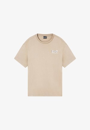 T-shirt beige a maniche corte con scollo rotondo e piccolo logo EA7 Emporio Armani sul petto a sinistra, posata distesa su sfondo bianco.