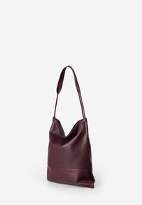 Borsa a spalla in pelle bordeaux con un design morbido, caratterizzata da una texture liscia e una tracolla larga. La parte inferiore ha una finitura leggermente diversa.