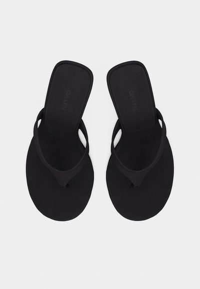 Ζευγάρι μαύρων σανδαλιών με σαγιονάρες με τετράγωνα πέλματα και απλές λουρίδες στα δάχτυλα, απεικονισμένα από πάνω σε απλό φόντο.