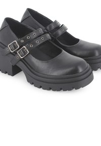 Zapatos Mary Jane de cuero negro con dos correas ajustables y herrajes plateados, que presentan una suela de plataforma gruesa con un relieve texturizado.