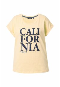 Světlě žluté tričko s krátkým rukávem, na kterém je výrazný námořnický modrý potisk "CALIFORNIA 1987" v tučném písmu. Vyrobeno z měkké bavlny, s volným střihem.