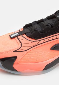 Korallfarvet og sort sneakers med tekstureret mesh-overdel, strømlinede linjer, sort snøresystem og en blank sort hælacksent.