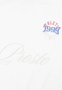 Biała koszulka bawełniana z niebiesko-czerwonym nadrukiem z napisem „ATHLETIC 1999” nad motywem piłki nożnej oraz słowem „Prosto” w jasnoszarym kolorze.