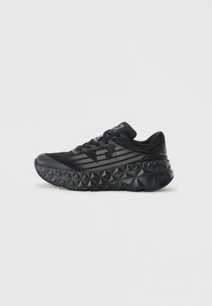 Black athletic sneaker with textured geometric sole, mesh side panels, and laces, displayed on a plain white background.