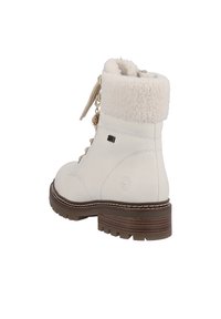 Witte leren enkellaars met een fuzzy crèmekleurige kraag, vetersluiting, decoratieve hardware en een bruin gelaagd, textuurgegeven zool.
