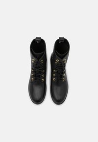 Botas de cuero negro hasta el tobillo con punta lisa, lados texturizados, ojales dorados y una lengüeta en la parte trasera. Adecuadas para diversas ocasiones.