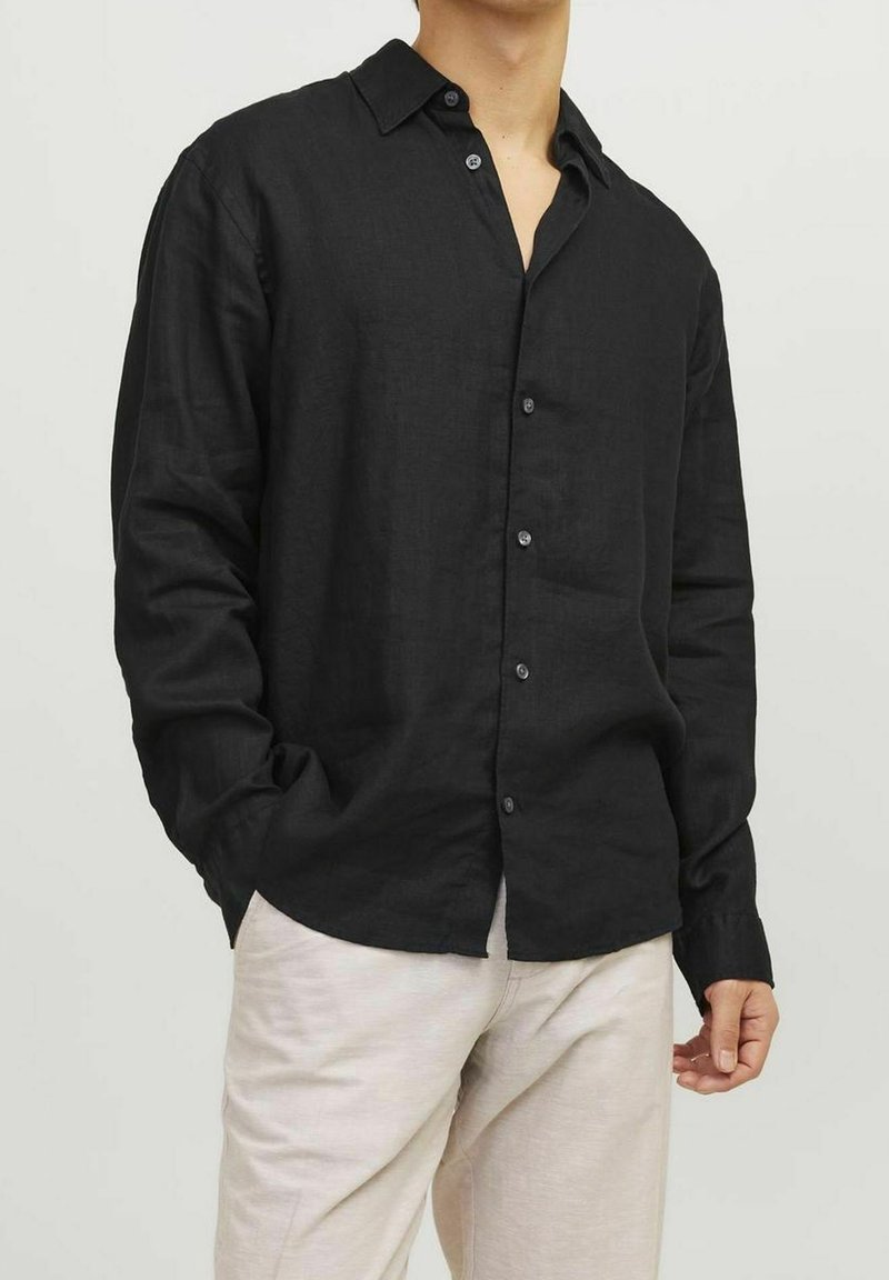 Camicia nera in lino con design a bottoni, maniche lunghe e colletto. Presenta una vestibilità comoda e una trama sottile. I bottoni sono di colore scuro.