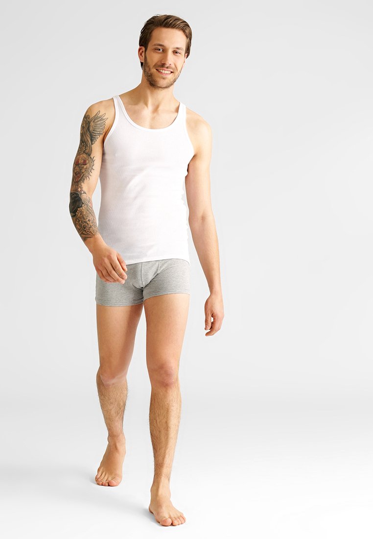 Ein weißes Baumwoll-Top und graue Boxershorts auf einer männlichen Figur, die eine lässige Passform zeigen. Hauttextur sichtbar; Tattoo-Design am linken Arm.