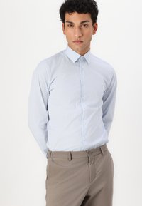 Lyseblå stripete dresskjorte med knappekrage, lange ermer og en tettsittende design, paret med beige bukser.