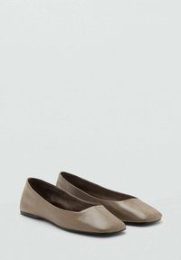 Par de bailarinas de cuero color topo con punta cuadrada y suelas negras, exhibidas sobre un fondo claro y sencillo.