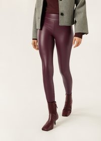 Bordeaux färgade leggings i konstläder med en glansig finish, tillsammans med en grå kort jacka och matchande bordeaux färgade stövletter.