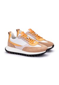 Sneaker tan e bianche con accenti arancioni, dotate di una tomaia in suede e pelle, una suola intermedia testurizzata e una suola esterna in gomma nera robusta.