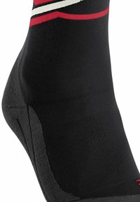 Chaussette de sport noire avec des rayures rouges et blanches, talon texturé, ajustement serré et design ergonomique. Fabriquée en tissu extensible pour un confort optimal.