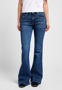 Uitgebrede blauwe denim jeans met een medium hoogte pasvorm, vijf-pocket ontwerp en subtiele vervaging. Bevat contrasterende stiksels en een lichte whiskering-effect.