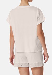 Vit bomull t-shirt med korta ärmar och avslappnad passform, tillsammans med vita shorts med broderade blommönster och utskärningar vid fållen.