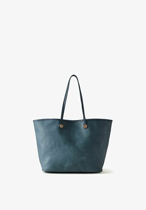 Sac cabas en cuir texturé bleu foncé avec deux fines bretelles et des détails de boutons métalliques ronds sur fond blanc.