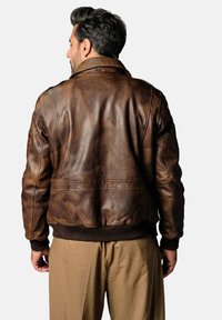 Veste aviateur en cuir marron avec un ourlet et des poignets côtelés, affichant une texture lisse et des variations de couleur subtiles, vue de dos.