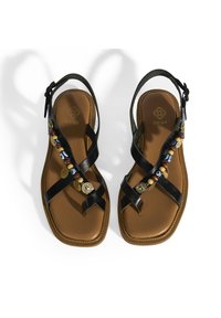 Schwarze Ledersandalen mit überkreuzten Riemen, verziert mit Perlen und goldfarbenen Akzenten, die auf einer braunen gepolsterten Sohle ruhen. Quadratförmig.