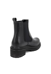 Stivaletto in pelle nera con pannelli laterali elasticizzati, suola nera spessa e linguetta sul retro. Texture liscia con una silhouette elegante.