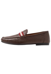 Mocassins en cuir marron avec une finition texturée, présentant un accent rayé rouge et blanc sur la partie supérieure et une semelle plate noire.