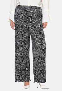 Czarno-białe spodnie o szerokich nogawkach z fakturowanej tkaniny. Elastyczny pas i luźny krój, zestawione z białymi szpilkami.