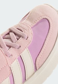 Baskets roses avec une combinaison de matériaux en daim et en maille, ornées d'accents et de lacets blancs, présentant un bout rond et une finition texturée.