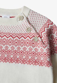 Strickpullover in Creme mit rotem gemustertem Design, runder Ausschnitt und drei Knöpfen an der Schulter zum Schließen. Weiche Textur.