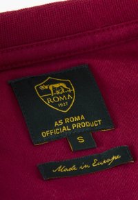 Bordeaux label met een schildlogo. Zwarte achtergrond met de tekst "AS ROMA OFFICIAL PRODUCT" en maat "S." Klein label leest "Made in Europe."