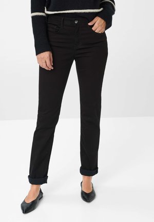 Zwarte straight-leg jeans met een ontwerp van voorzakken, opgerolde boorden en een soepele stofstructuur, gecombineerd met zwarte platte schoenen.