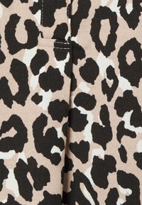 Tecido de padrão de leopardo com fundo bege e manchas pretas e brancas. Textura suave com detalhe de costura visível.