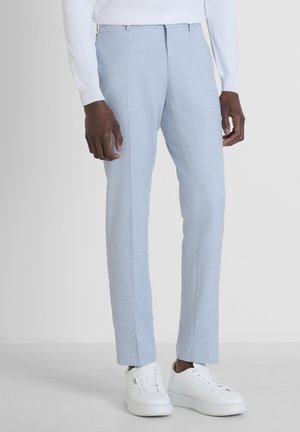 Lichtblauwe op maat gemaakte broeken van gladde stof met een subtiele textuur, met een slim fit en gecombineerd met witte sneakers.