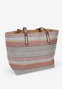 Borsa a tote a righe realizzata in tessuto intrecciato rosso, bianco e nero con manici in pelle marrone e dettagli a zigzag vicino al bordo superiore.