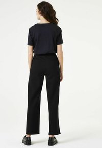 Zwarte wijde broek met hoge taille, gecombineerd met een kortgestructureerd zwart katoenen shirt. Glad textuur, minimale details en geen zichtbare logo's.